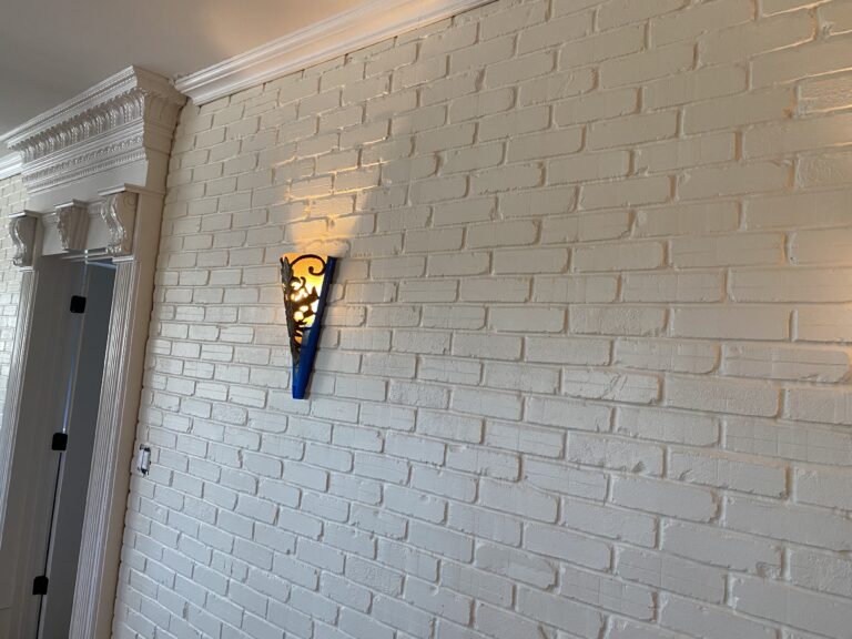 Shows a painted brick wall illuminated partially by a mounted lantern.