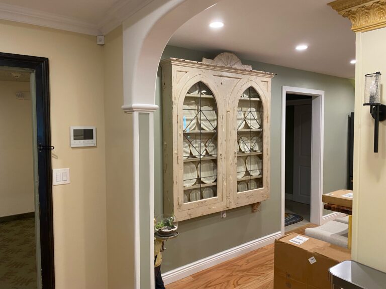 Shows a closet filled with plates, the walls behind it are painted in a nice green.