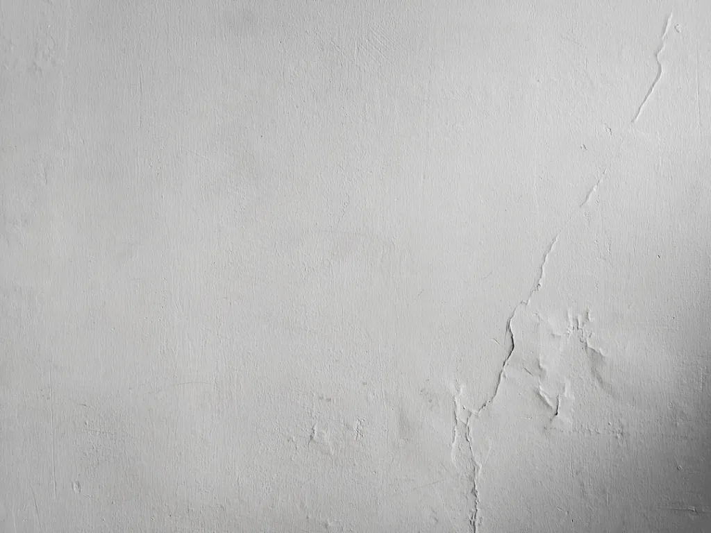 A white painted wall, with cracks forming across the right side.