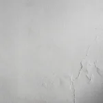A white painted wall, with cracks forming across the right side.