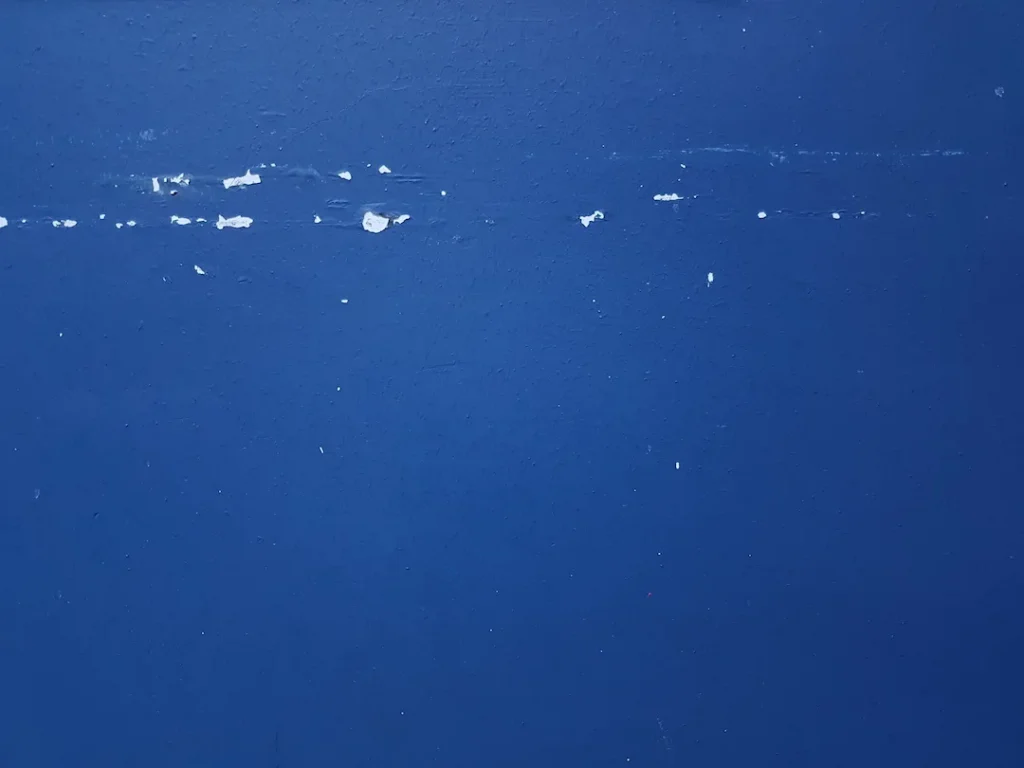 blue wall paint with some white specs missing