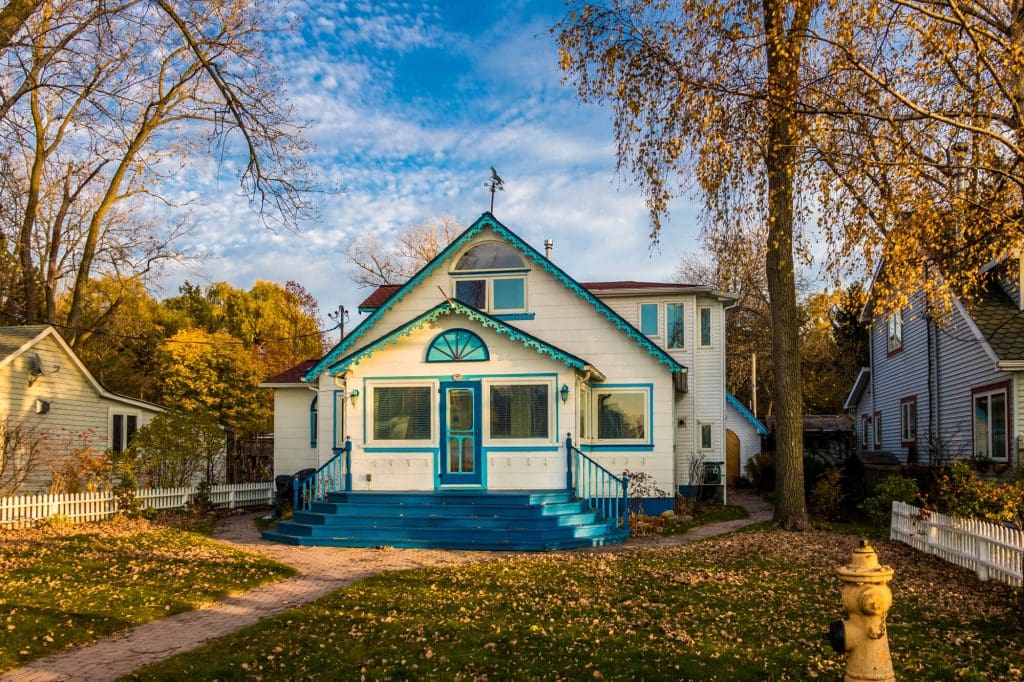 Two-story white house with bright blue trim and steps, surrounded by autumn trees in Ocean County, NJ.