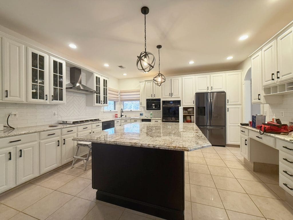 Kitchen with refinished white cabinets and a dark island.