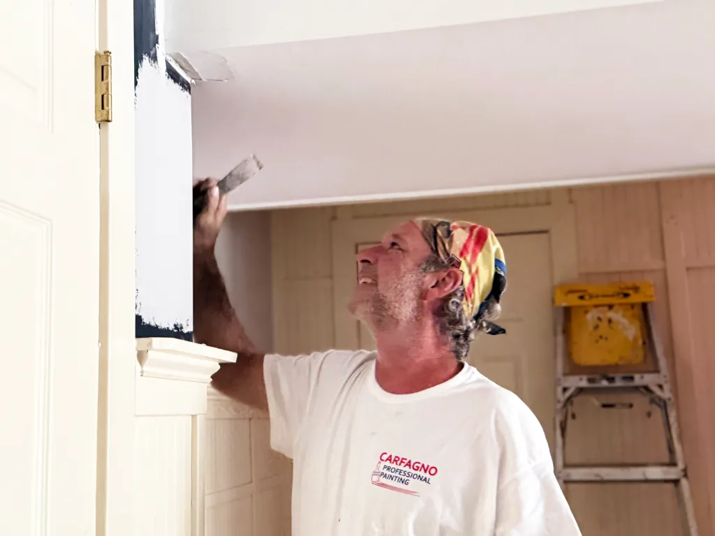 Carfagno painter brushing dark paint onto interior trim.